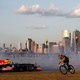 A photo of a Red Bull F1 car driving in New Jersey with the New York skyline in the background.